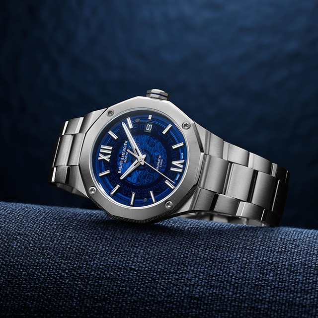 A watch with dark blue shield and a steel strap