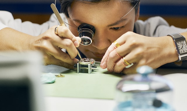 A photo of a person in a workshop assembling a watch